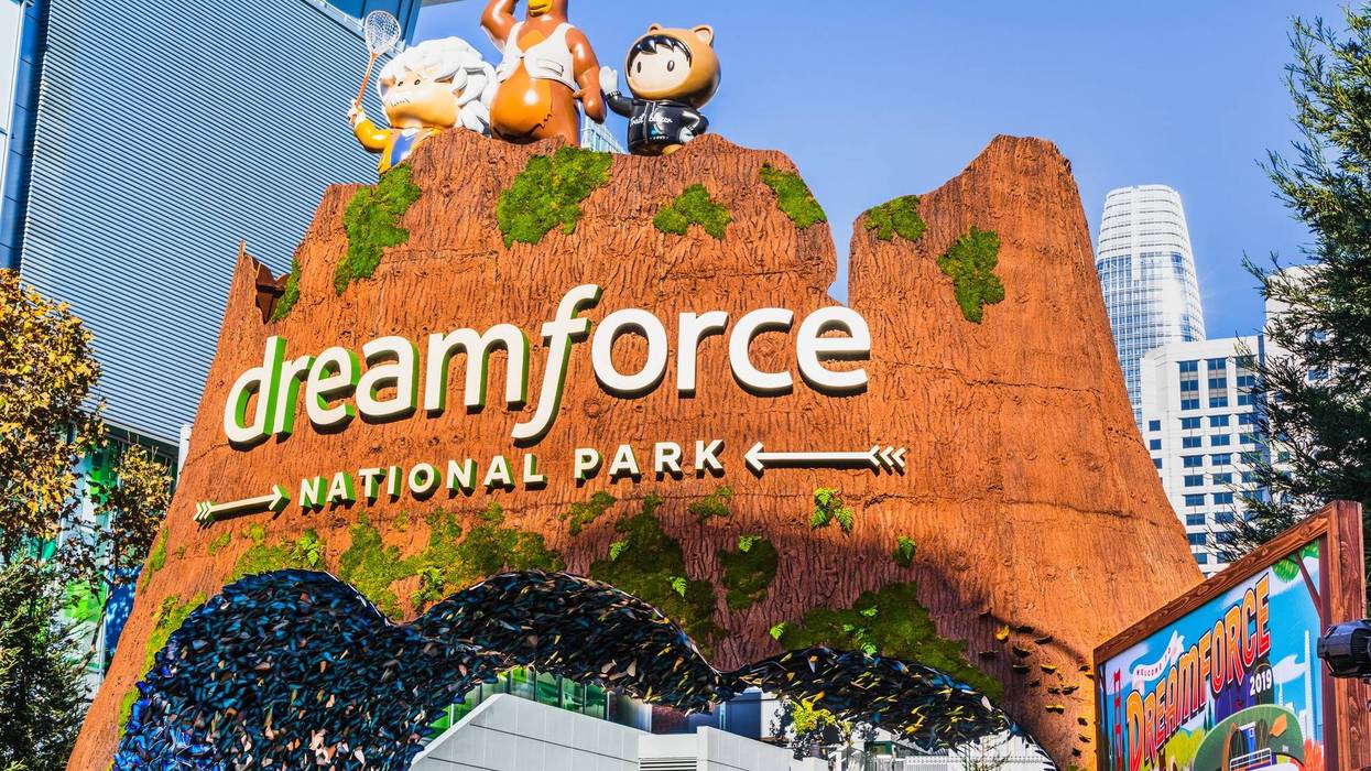 Rocky-façade entrance structure with Dreamforce National Park attached to it with some of the San Francisco skyline in the background.