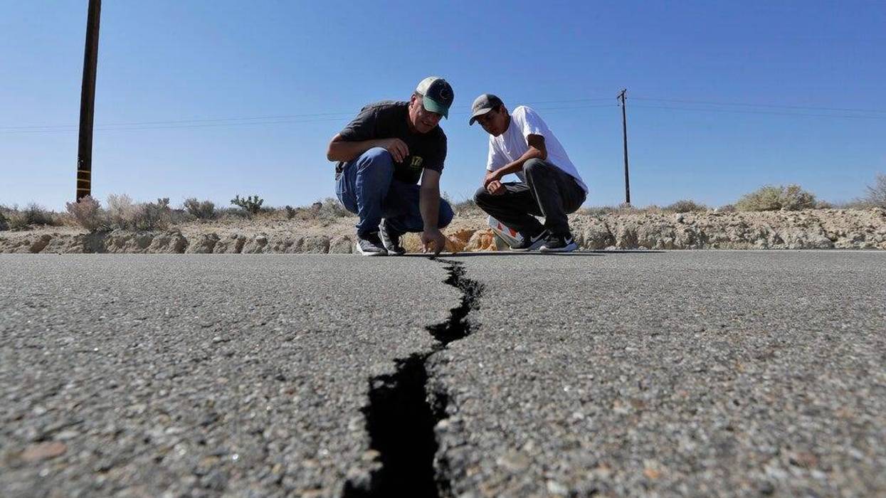 Ron Mikulaco, left, and his nephew, Brad Fernandez, examine a crack caused by an earthquake on highway 178