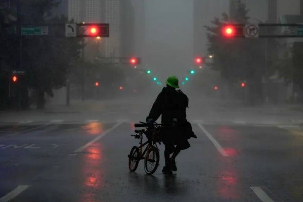 Ron Rook, who said he was looking for people in need of help or debris to clear, walks through windy and rainy conditions on a deserted street in downtown Tampa during the approach of Hurricane Milton