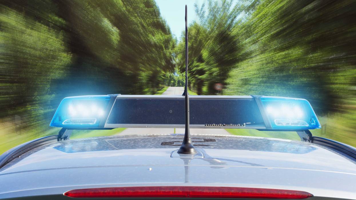 roof of a police car with flashing siren light s driving fast on a country road