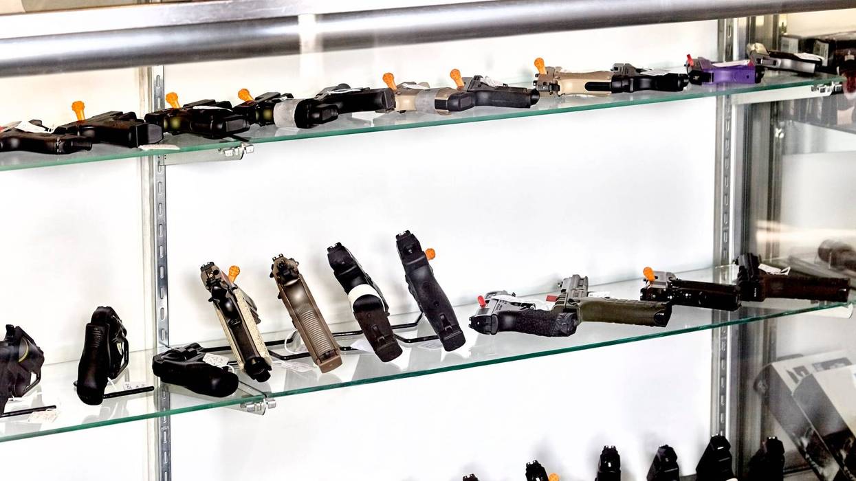 Rows of guns for sale in showcase of retail store with application on counter