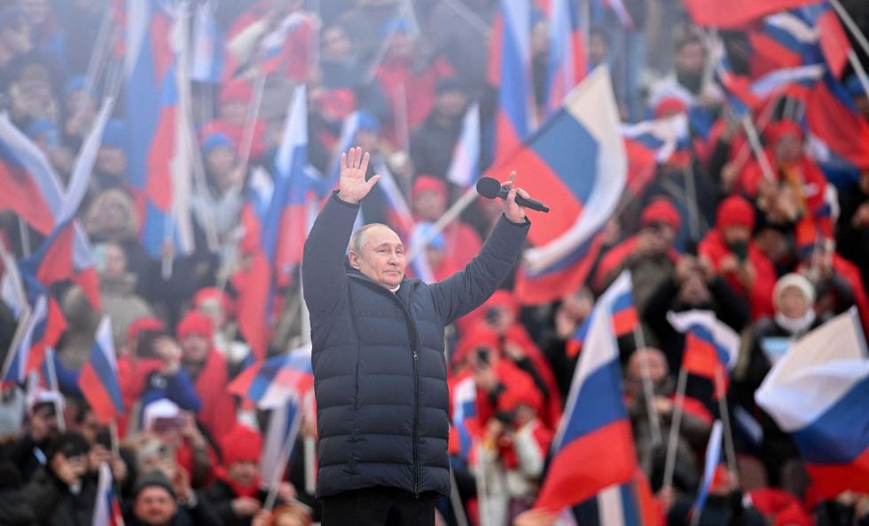 Russian President Vladimir Putin greets the audience as he attends a concert marking the eighth anniversary of Russia