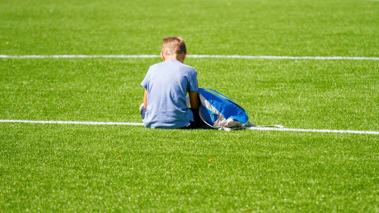 Sad kid sitting on soccer field