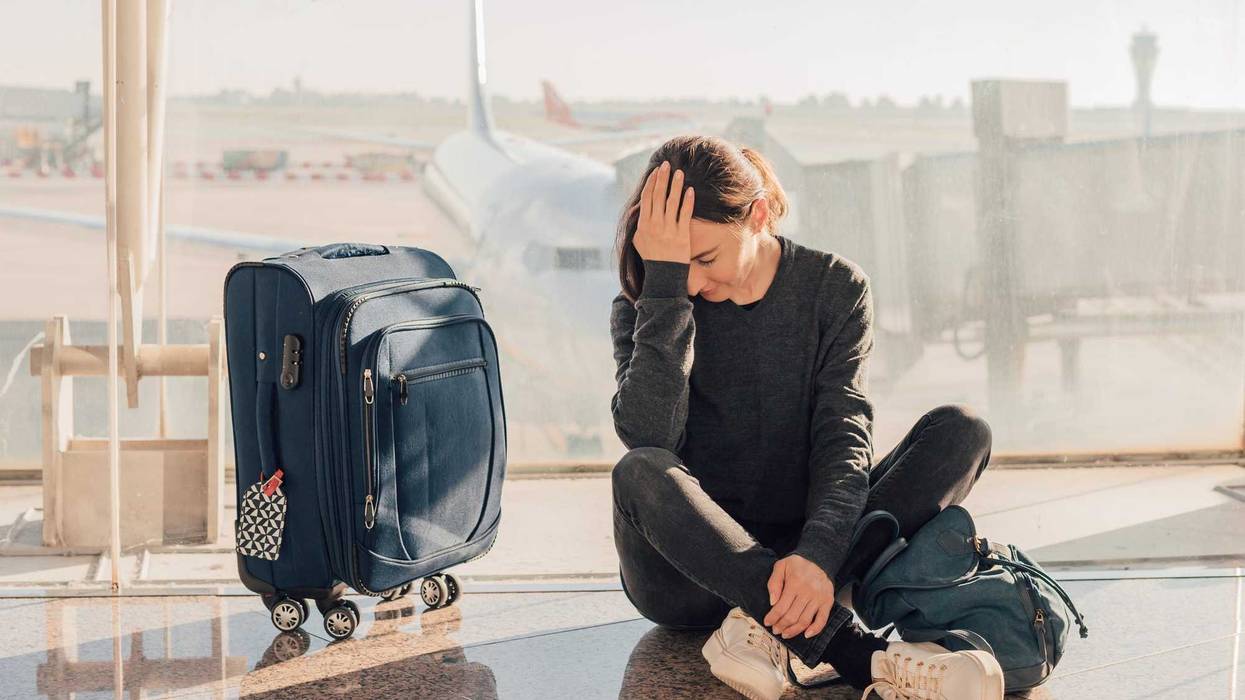 Sad (tired) woman sitting in the airport - missed or cancelled flight concept.