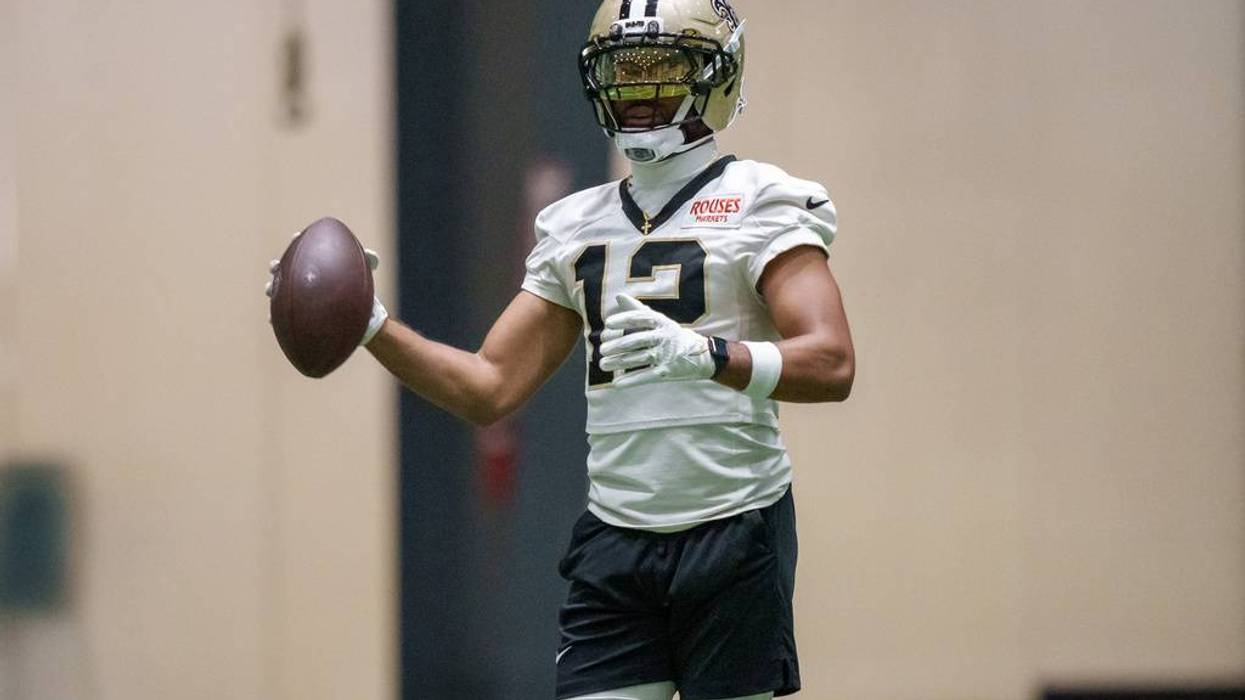 Saints player #13 in gold helmet with dark visor and white jersey, holding a football.