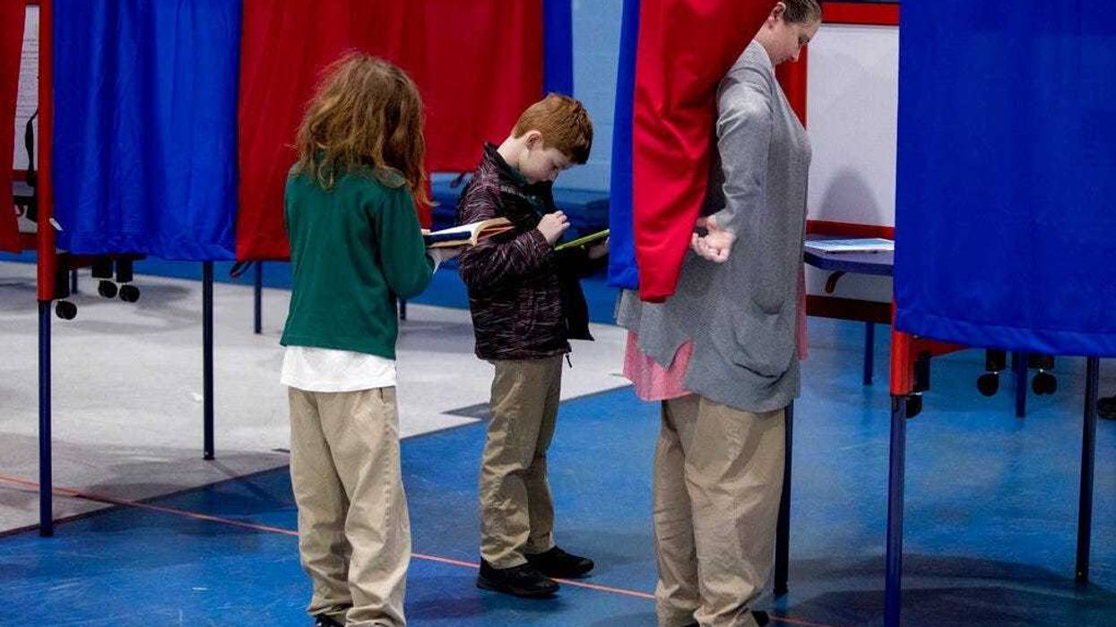 Samantha Murch accompanied by her two boys Alexander, 8, center, and Jacob, 11, left, votes in the New Hampshire primary at Bishop O'Neill Youth Center, Tuesday, Feb. 11, 2020, in Manchester, N.H. (AP Photo/Andrew Harnik)