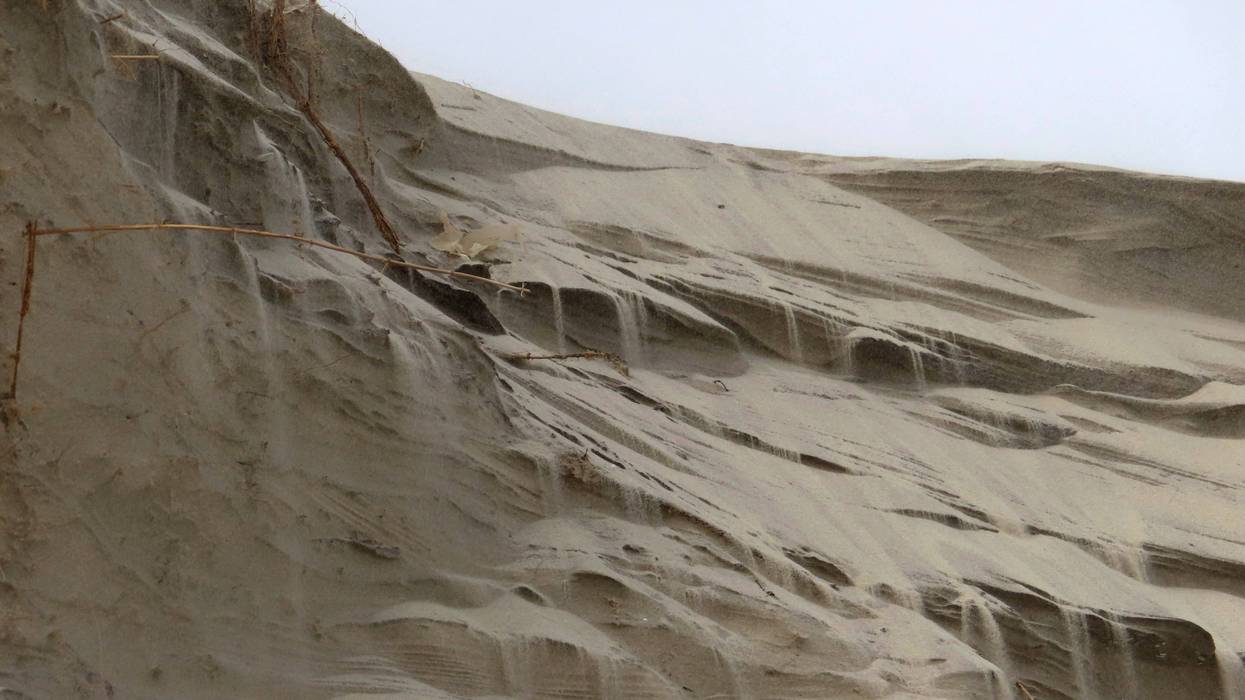 Sand cascades down the badly eroded face of a dune in North Wildwood, N.J. on Feb. 24, 2023.