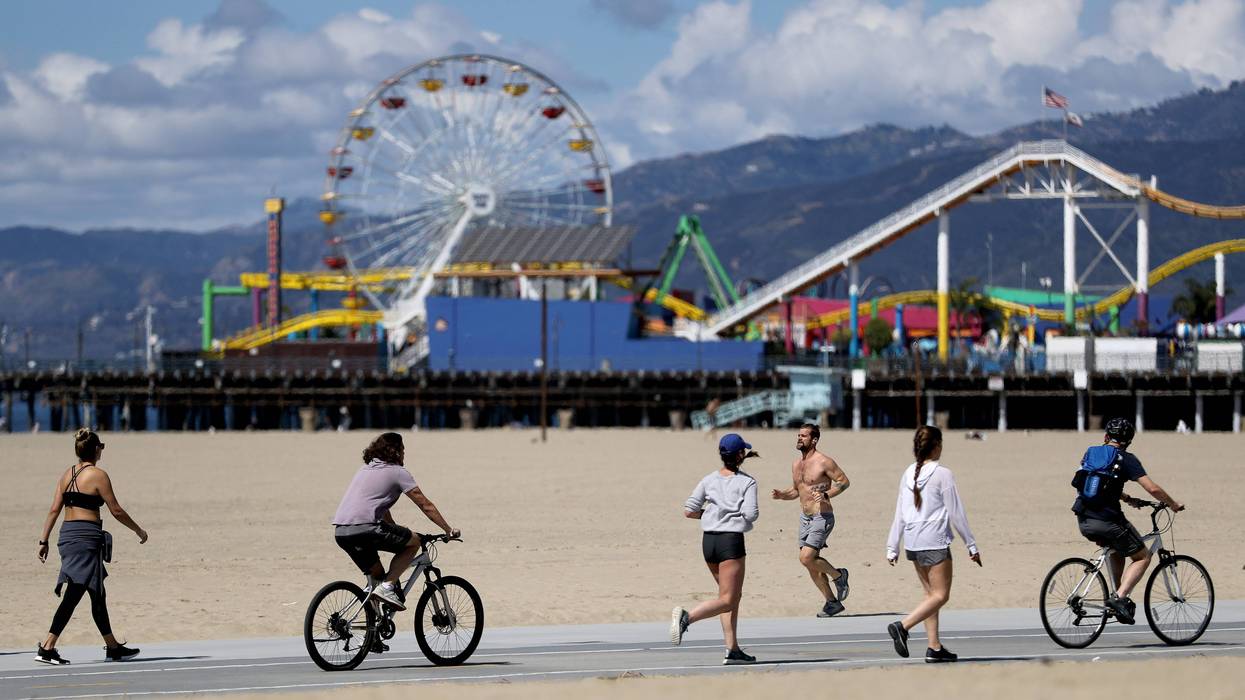 SANTA MONICA, CALIFORNIA - MARCH 21: People exercise on Santa Monica beach in front of the shuttered Santa Monica Pier on March 21, 2020 in Venice, California.