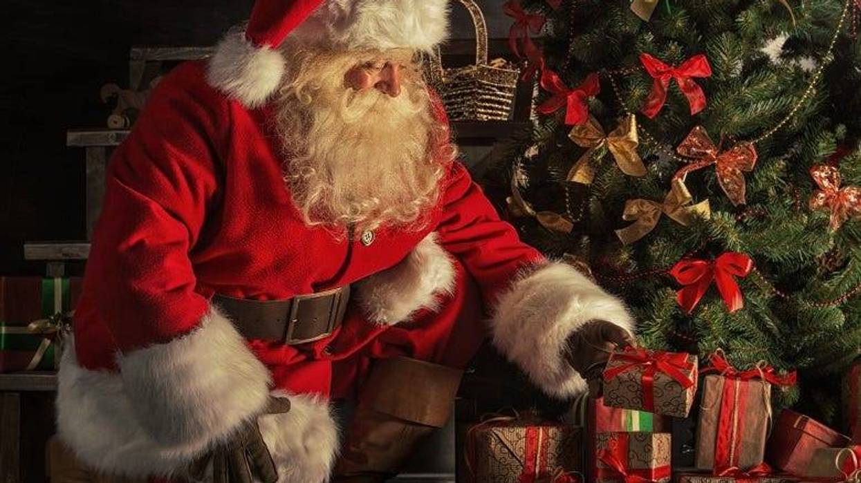 Santa with gifts under Christmas tree