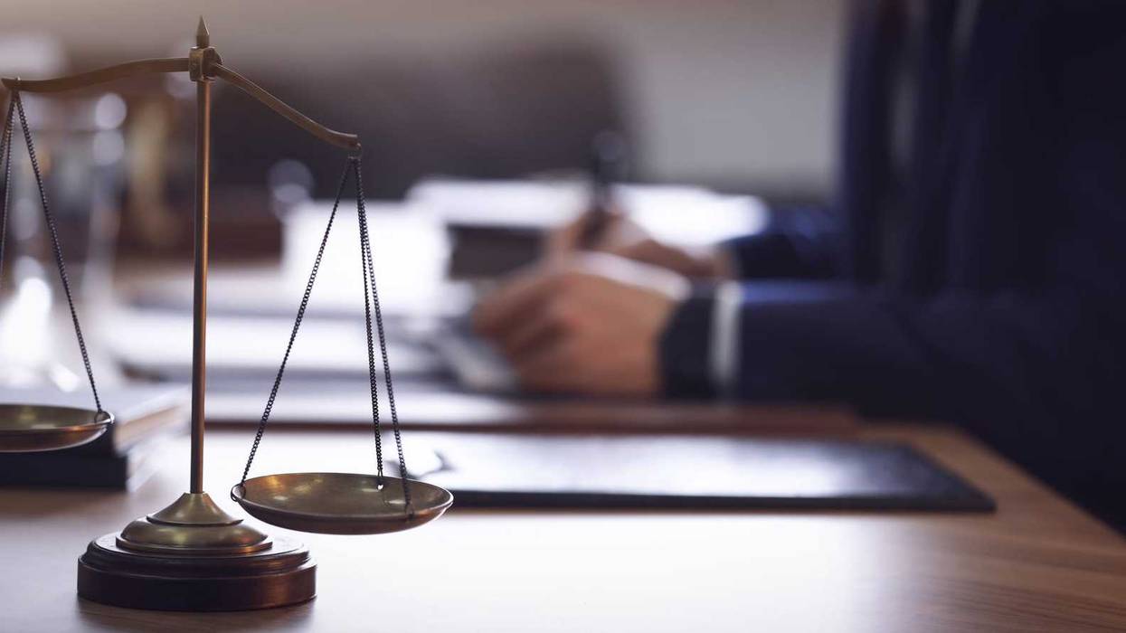 Scales of justice and a lawyer at a desk.