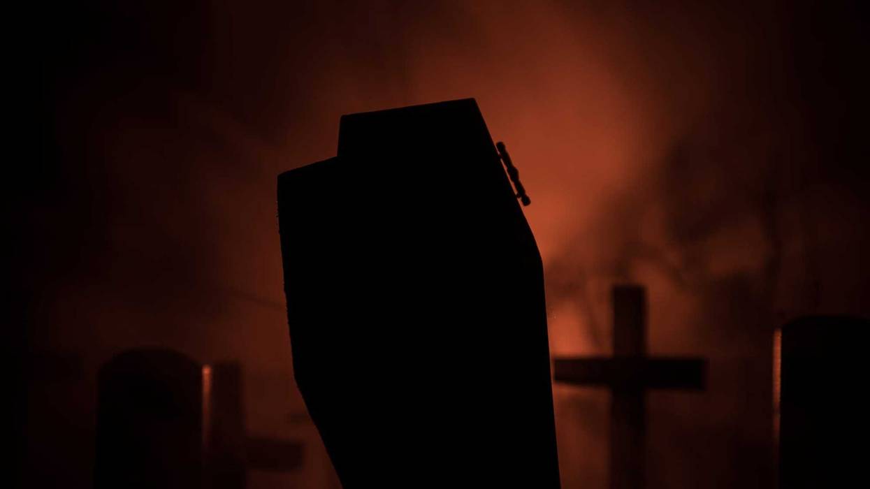 Scary coffin backed by red light and fog, stock photo.