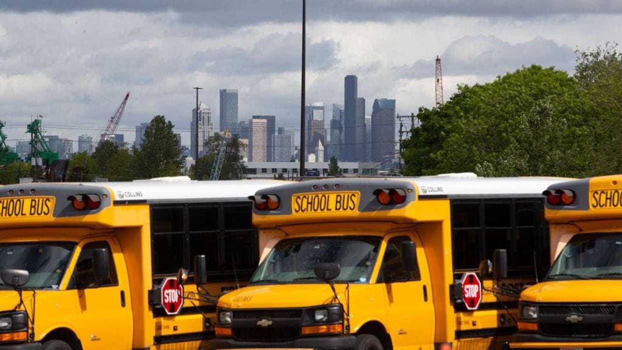 School buses sit idle in a bus yard.