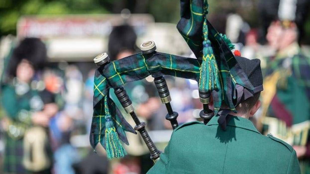Scottish festival with the back of a bag piper playing with a larger band