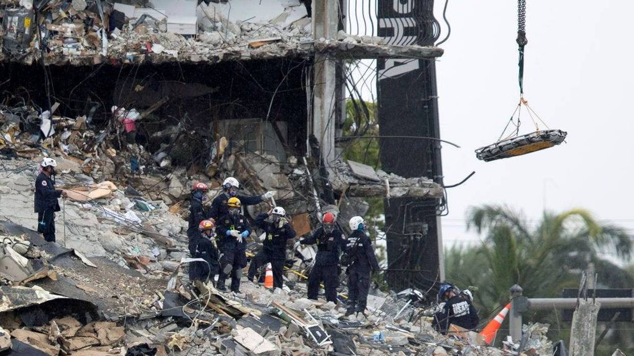Search an Rescue personnel use a crane to remove a stretcher from the rubble of the partially collapsed 12-story Champlain Towers South condo building on June 28, 2021 in Surfside, Florida.