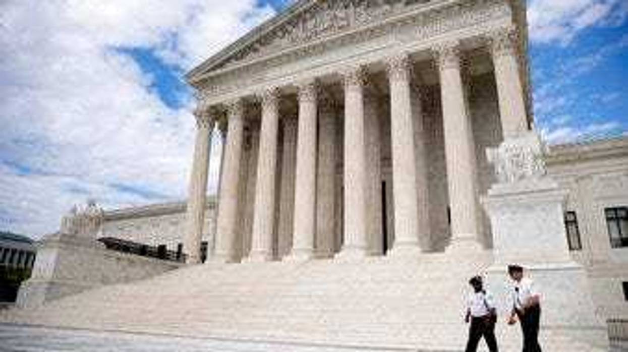 Security officers, one wearing a mask, walk in front of the Supreme Court, Thursday, May 14, 2020, in Washington. (AP Photo/Andrew Harnik)