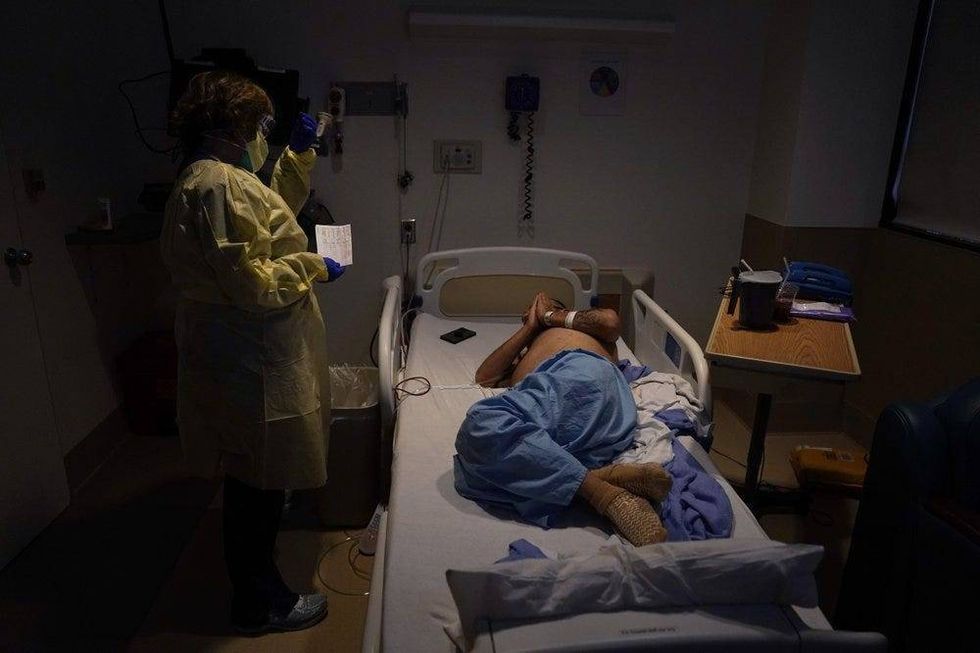 Senior chaplain Nancy Many, left, prays with Rafael Lopez in a COVID-19 unit.