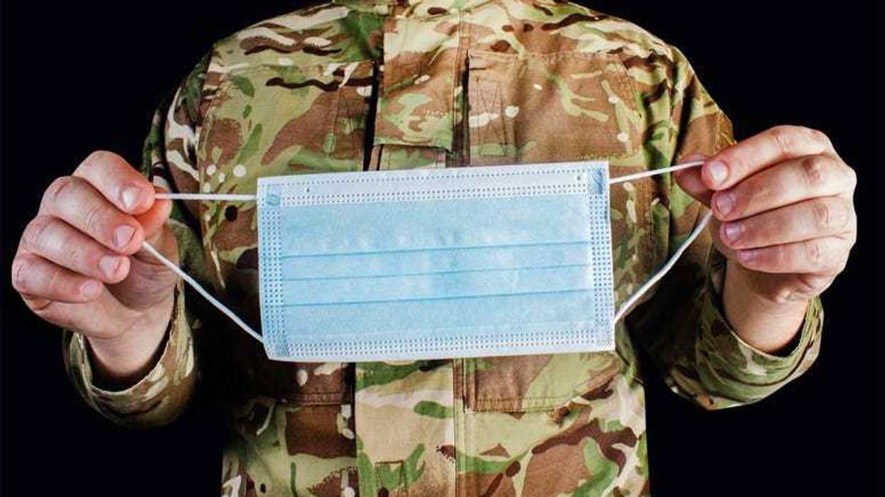 Service member holding a mask.