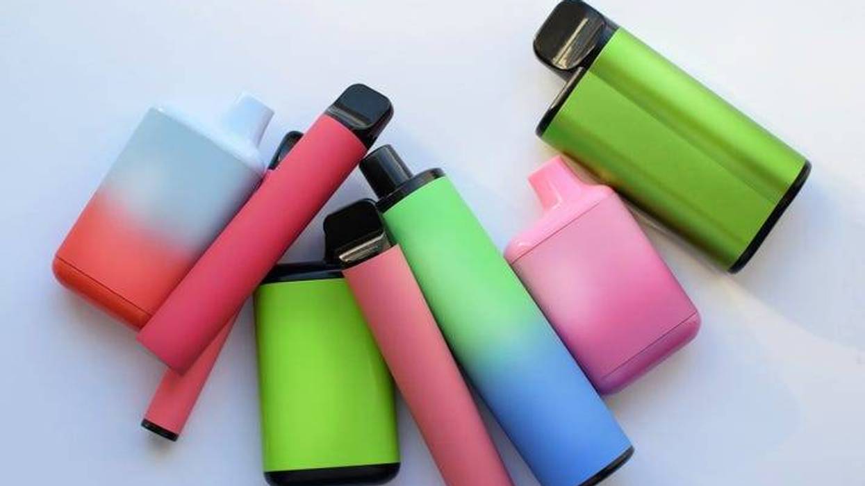 Several multi-colored electronic cigarettes lie on a light table.