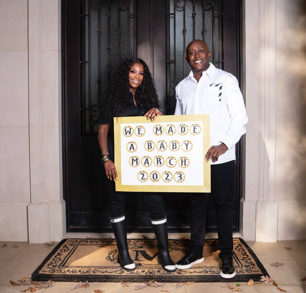 Shamea Morton and her husband, Gerald Mwangi holding a sign that reads "we made a baby, March 2023."