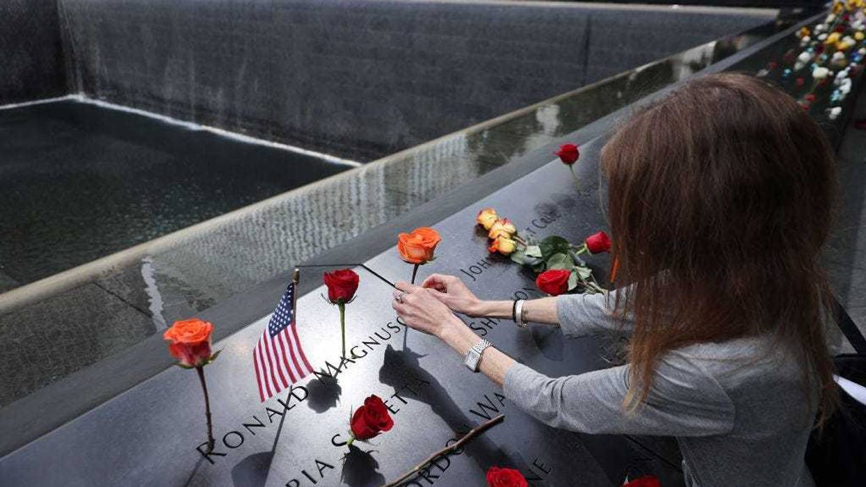 Sheryl Magnuson places a flower in her father's name where it is inscribed on the National 9/11 Memorial south pool following the commemoration ceremony at the memorial on September 11, 2021 in New York City.