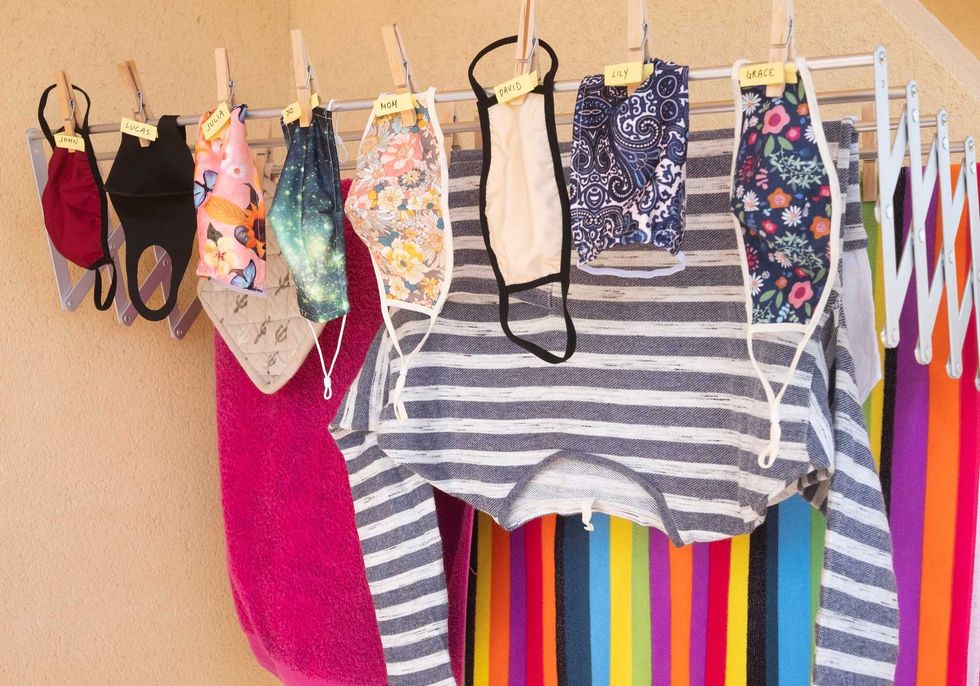 Shirts, masks and other clothing items on an inside clothes line.