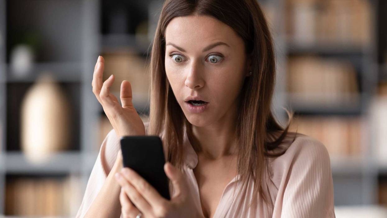 Shocked young woman looking at her smartphone.