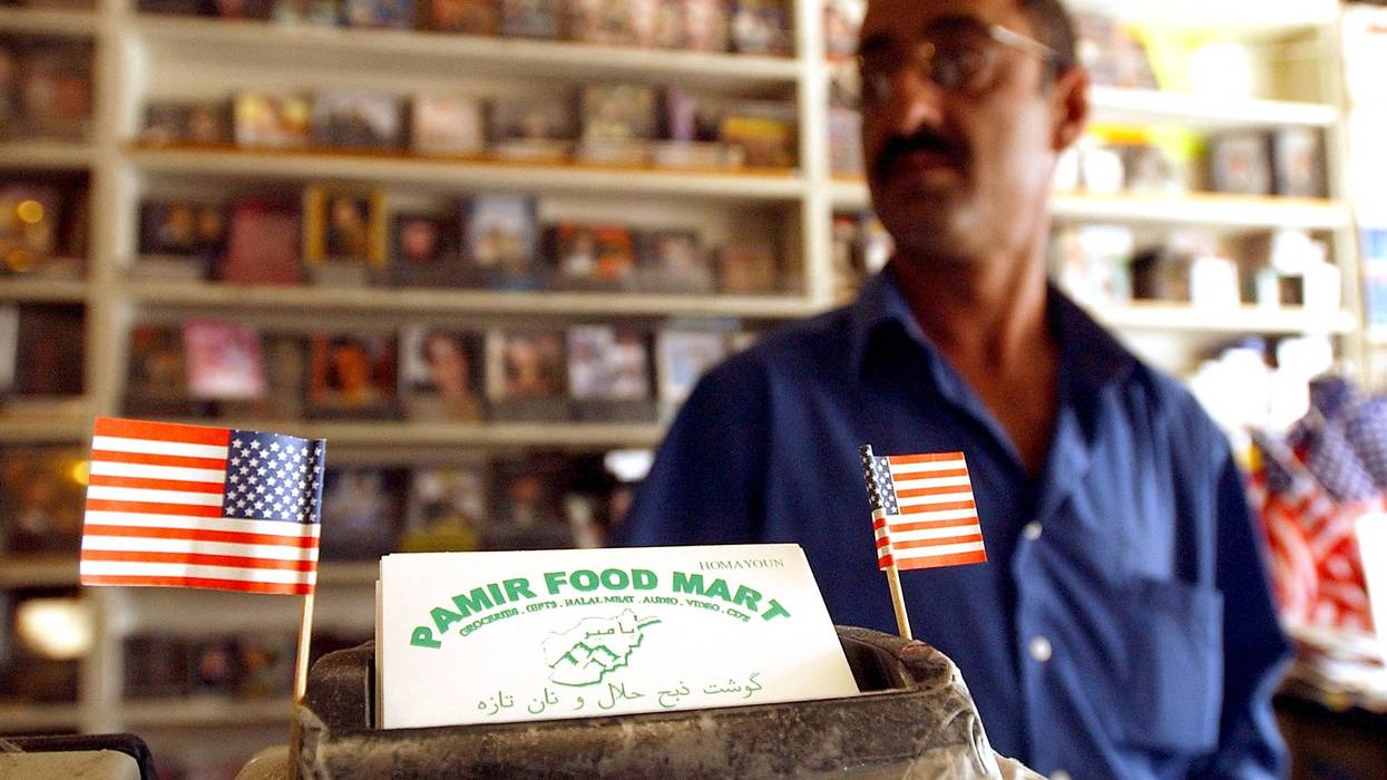 Shopkeeper Homayoun Khamosh displays American flags next to his business cards October 24, 2001 at the Pamir Food Mart in the "Little Kabul" district of Fremont, CA.