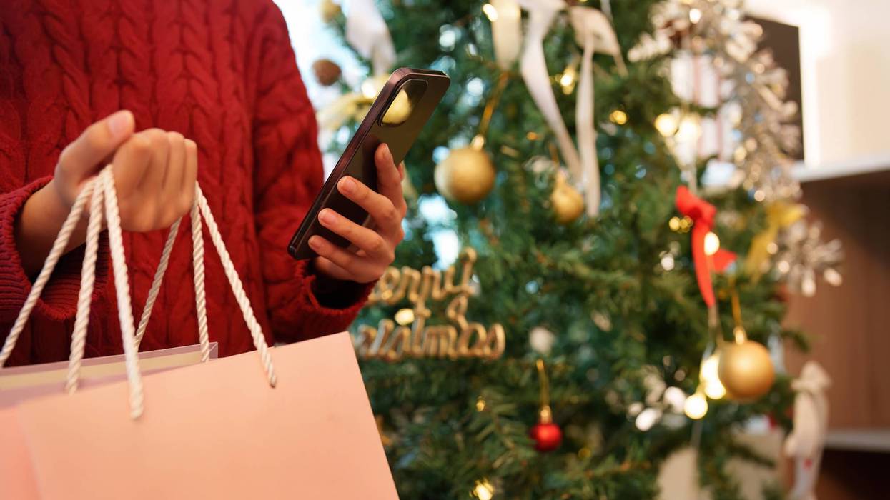 Shopping bags and smartphone near Christmas tree