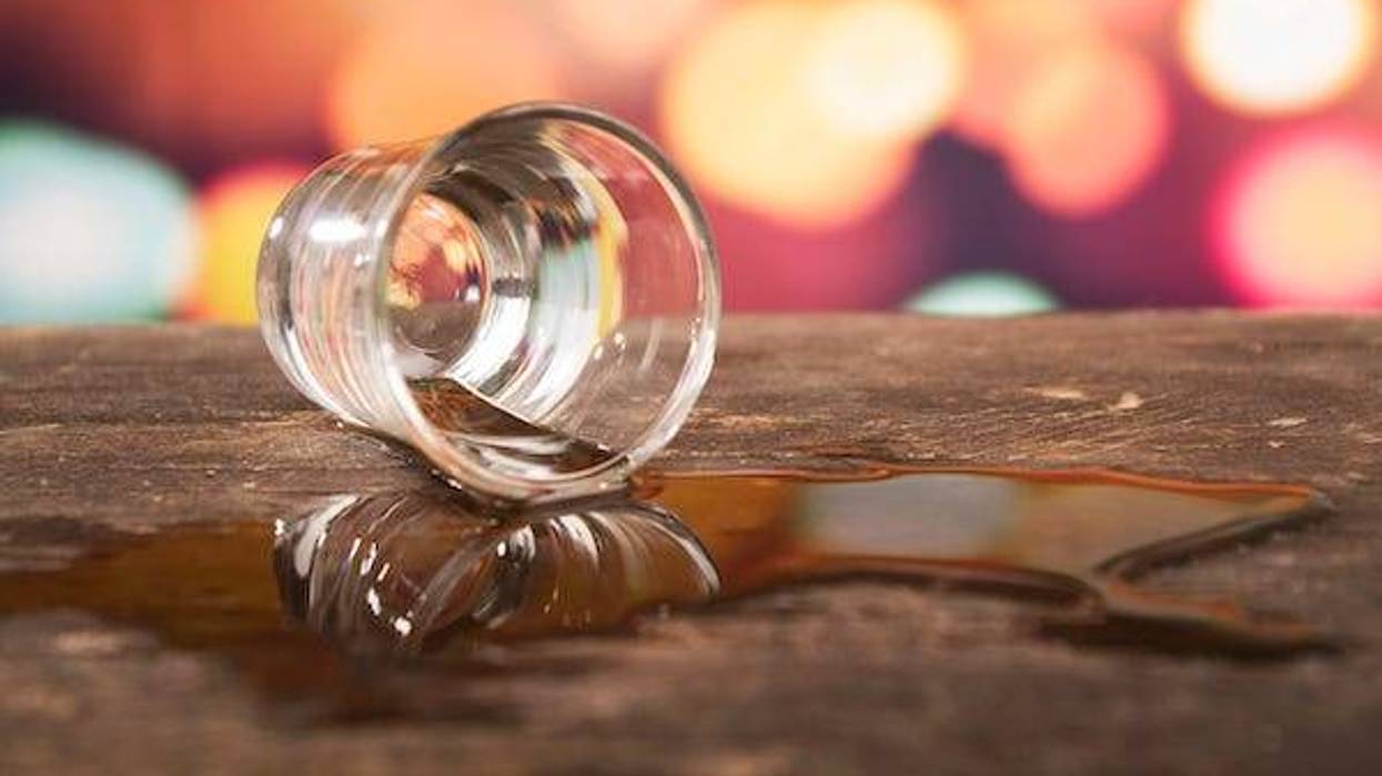 Shot glass of whiskey spilled on a bar