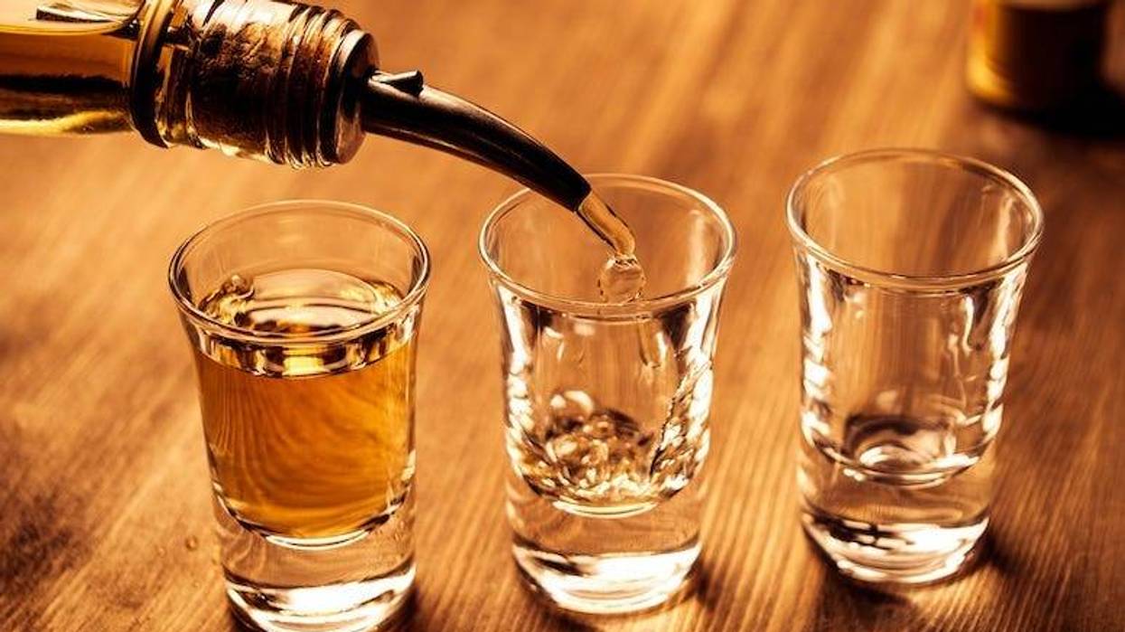 Shots of alcohol are being poured into shot glasses.