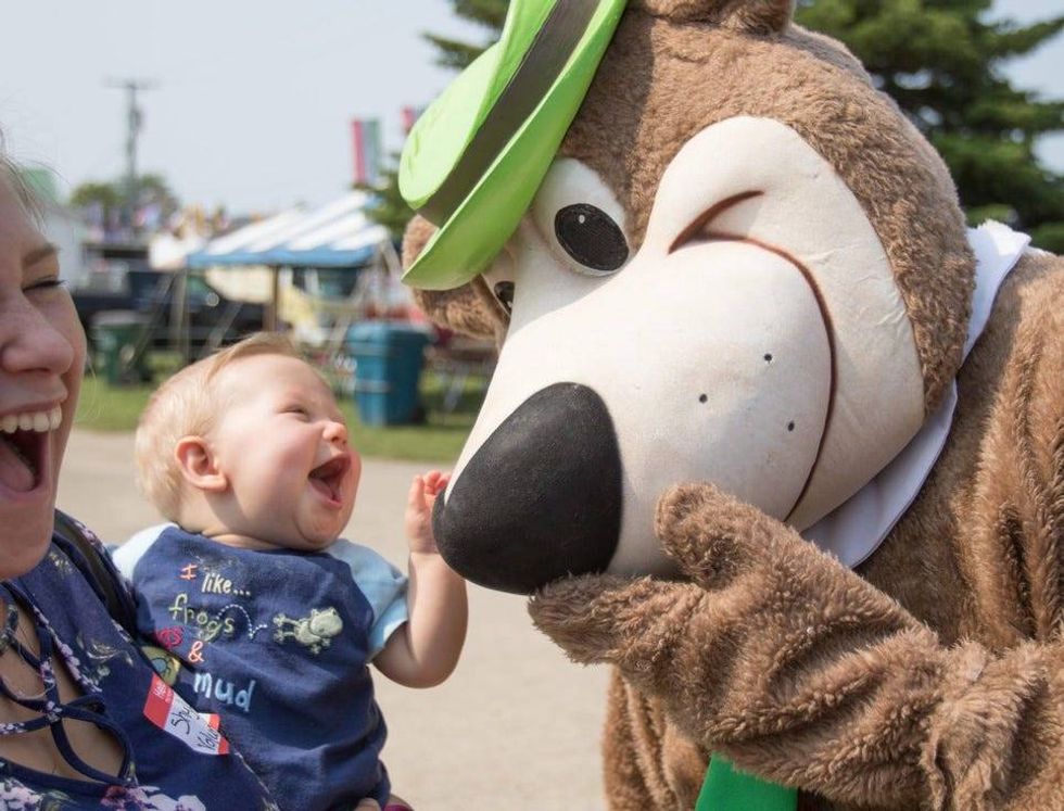 ShyLinn Sporer, left, laughs as she holds her nephew 7 1/2-month-old Sebastian Sporer, thrilled to meet Yogi Bear at the Fowlerville Family Fair Thursday, July 25, 2019.