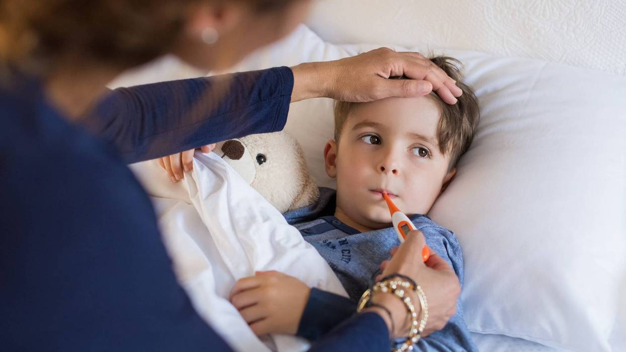 Sick boy with thermometer laying in bed