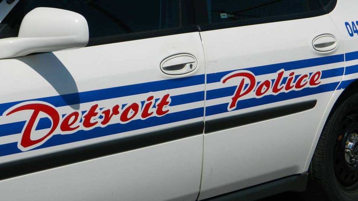 Side of a white Detroit Police car with red "Detroit Police" text over blue stripes.