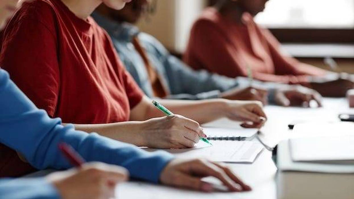 Side view close up of students in row taking notes during lecture in college classroom