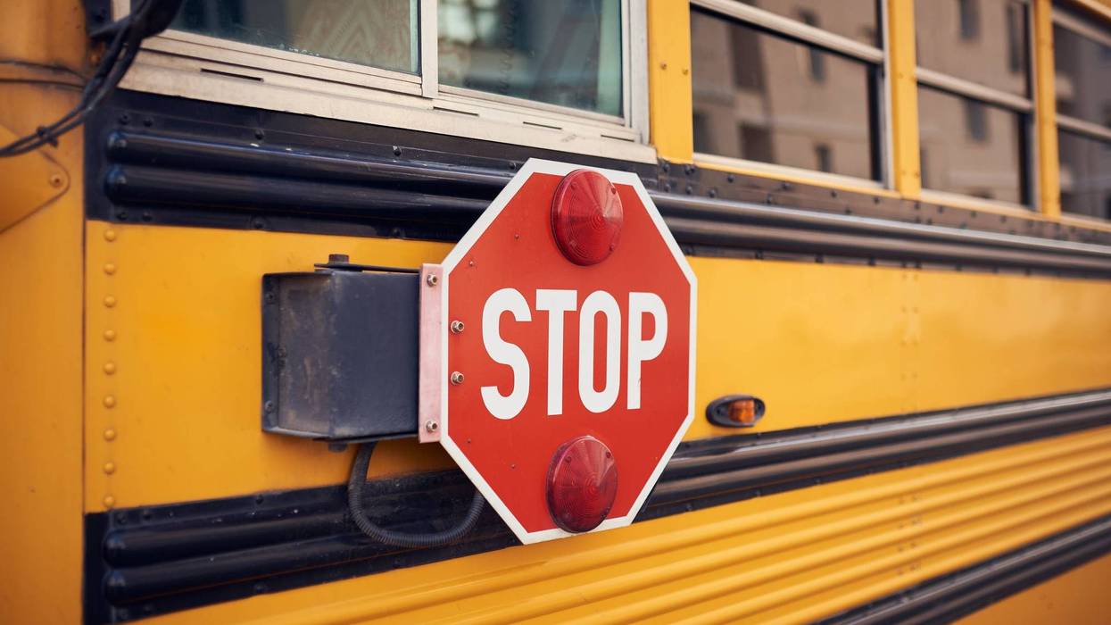 Side view of a school bus and its stop signal.