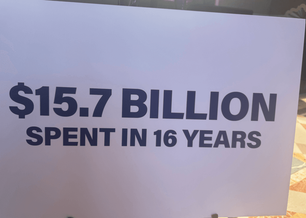 sign at the press conference that says "$15.7 Billion spent in 16 years"