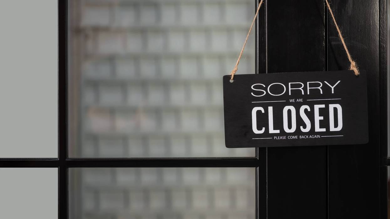 Signboard of tell sorry we are closed business and please come back again when situation improved with hanging to door front at shop. Text written Sorry we're closed hang on mirror door at restaurant.