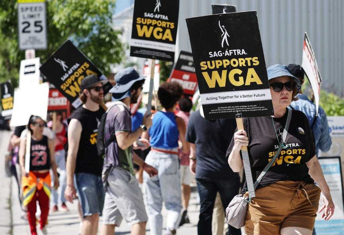Signs read 'SAG-AFTRA Supports WGA' as SAG-AFTRA members walk the picket line in solidarity with striking WGA (Writers Guild of America) workers outside Netflix offices on July 11, 2023 in Los Angeles, California.