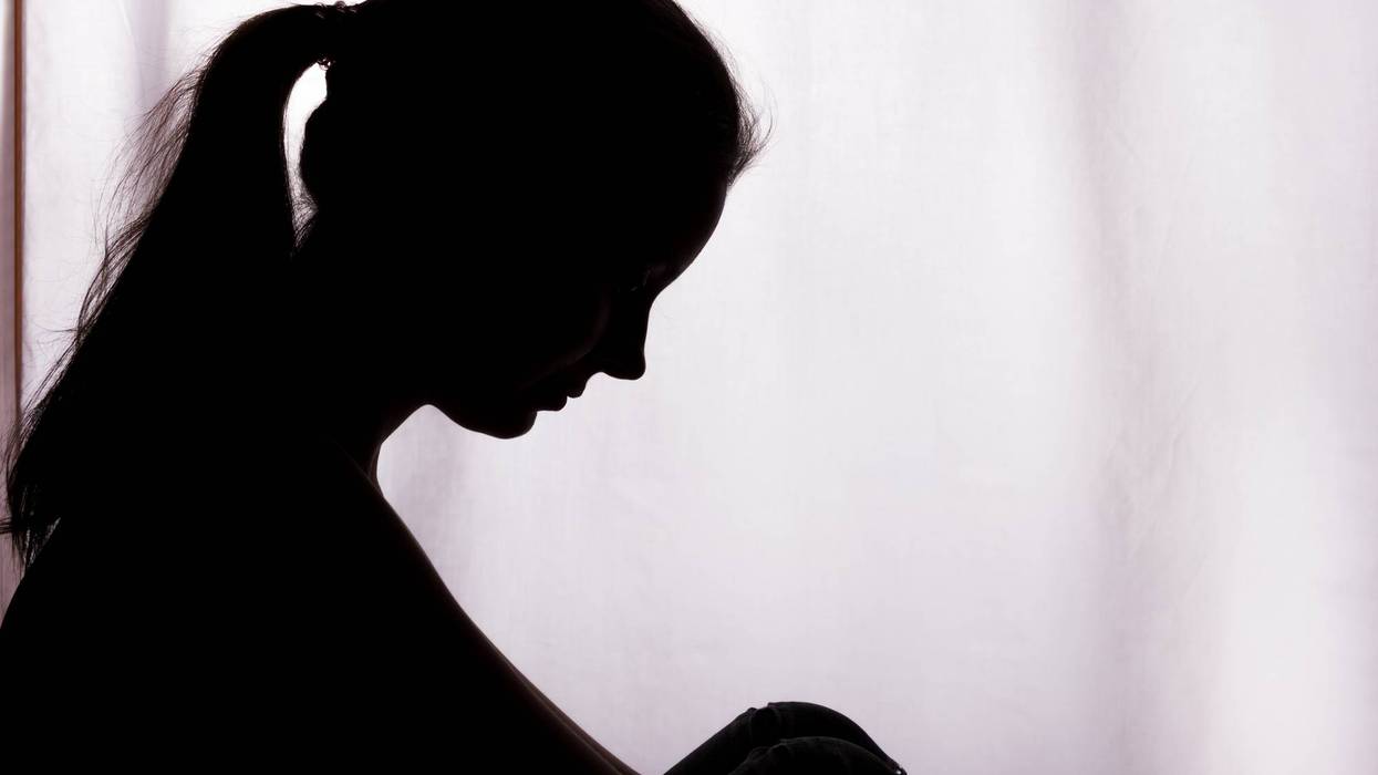 Silhouette of a person with a ponytail, head bowed in sadness.
