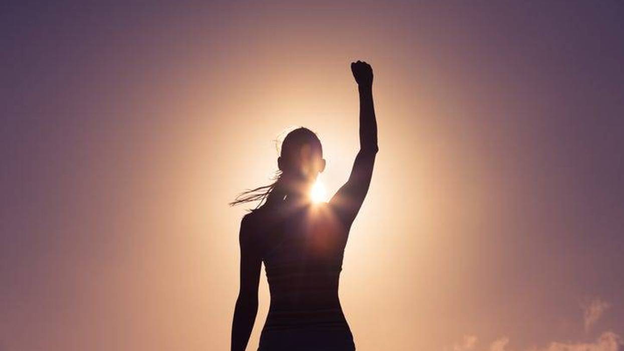 Silhouette of a strong confident woman with fist raised