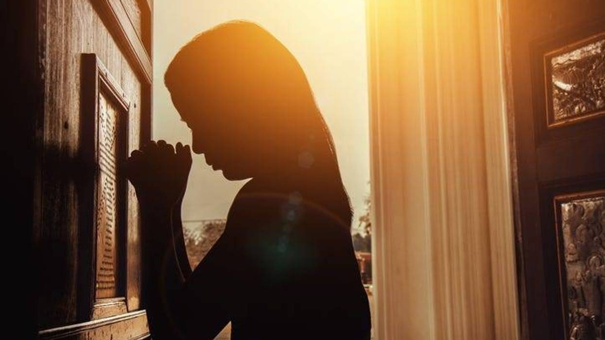 silhouette of woman kneeling and praying