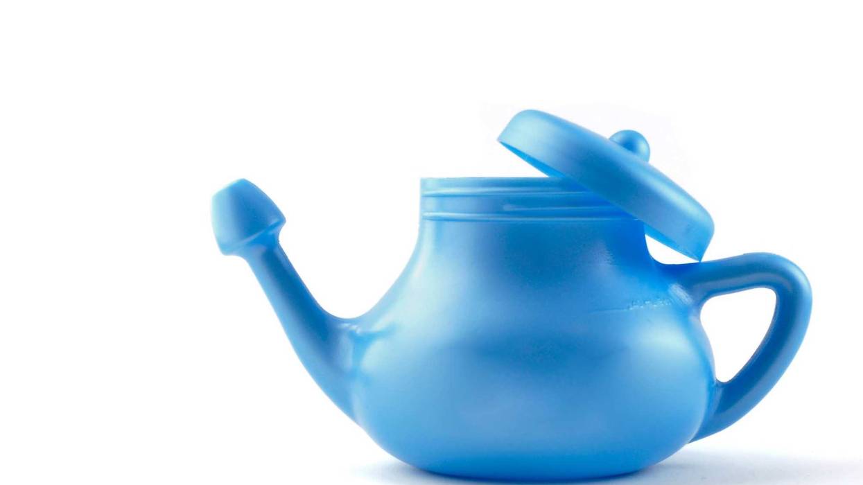 Sinus rinse stock photo. Blue neti pot against a white background.