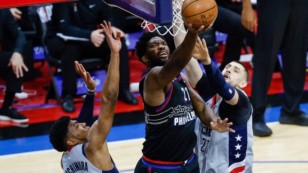 Sixers center Joel Embiid shoots between Wizards forward Rui Hachimura and center Alex Len during the second quarter during Game One of the Eastern Conference first round series at Wells Fargo Center on May 23, 2021.