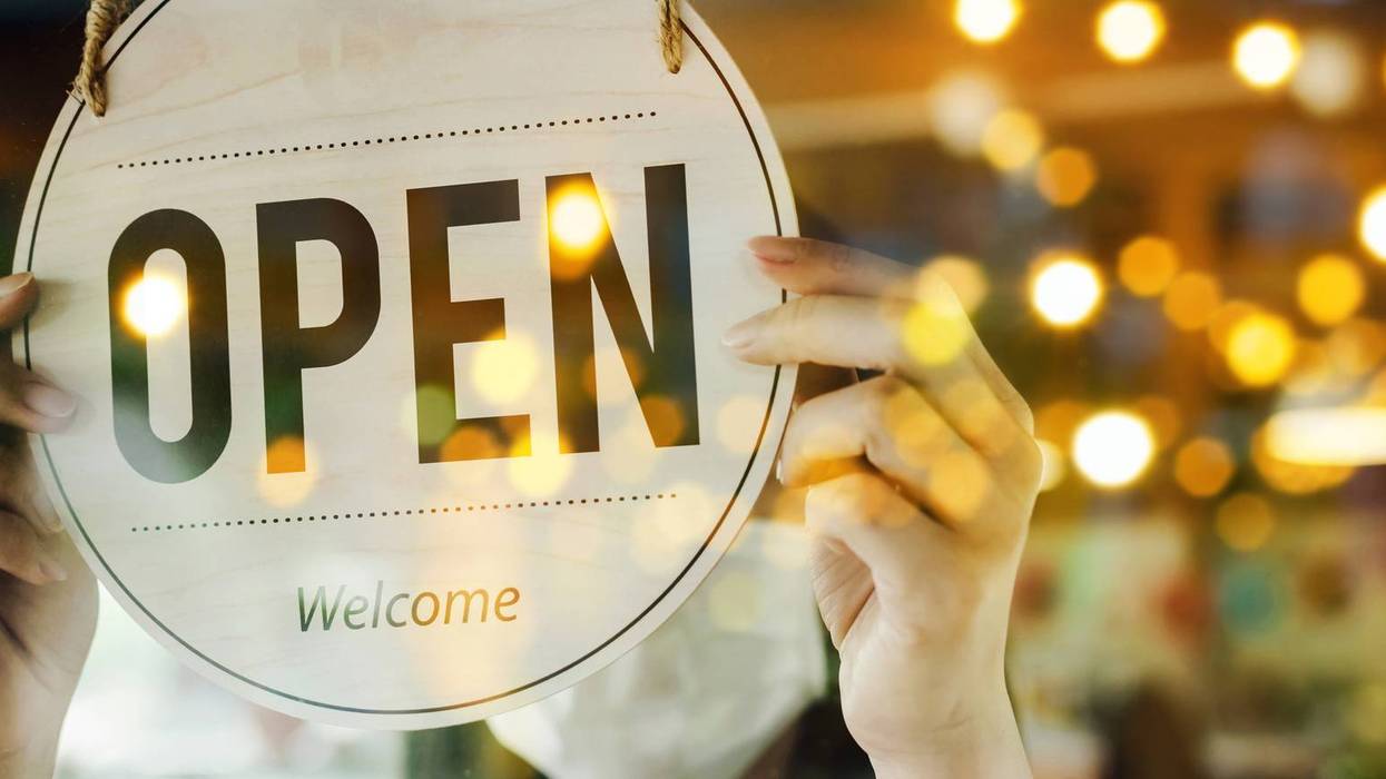 Small business owner hangs "Open" sign in the window
