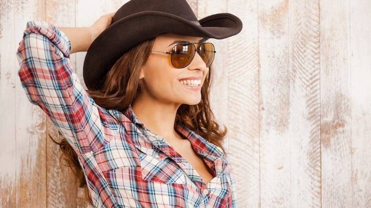 Smiling cowgirl leaning against a wooden wall