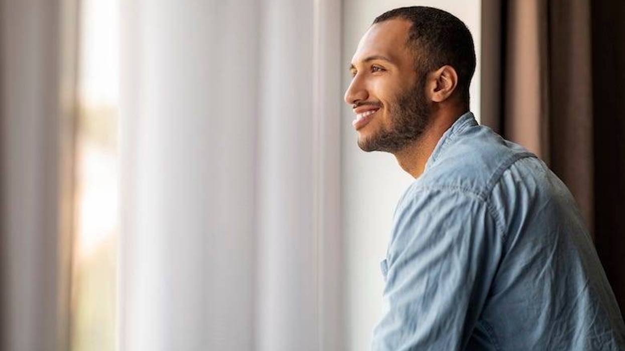 Smiling man starting out of the window at his home