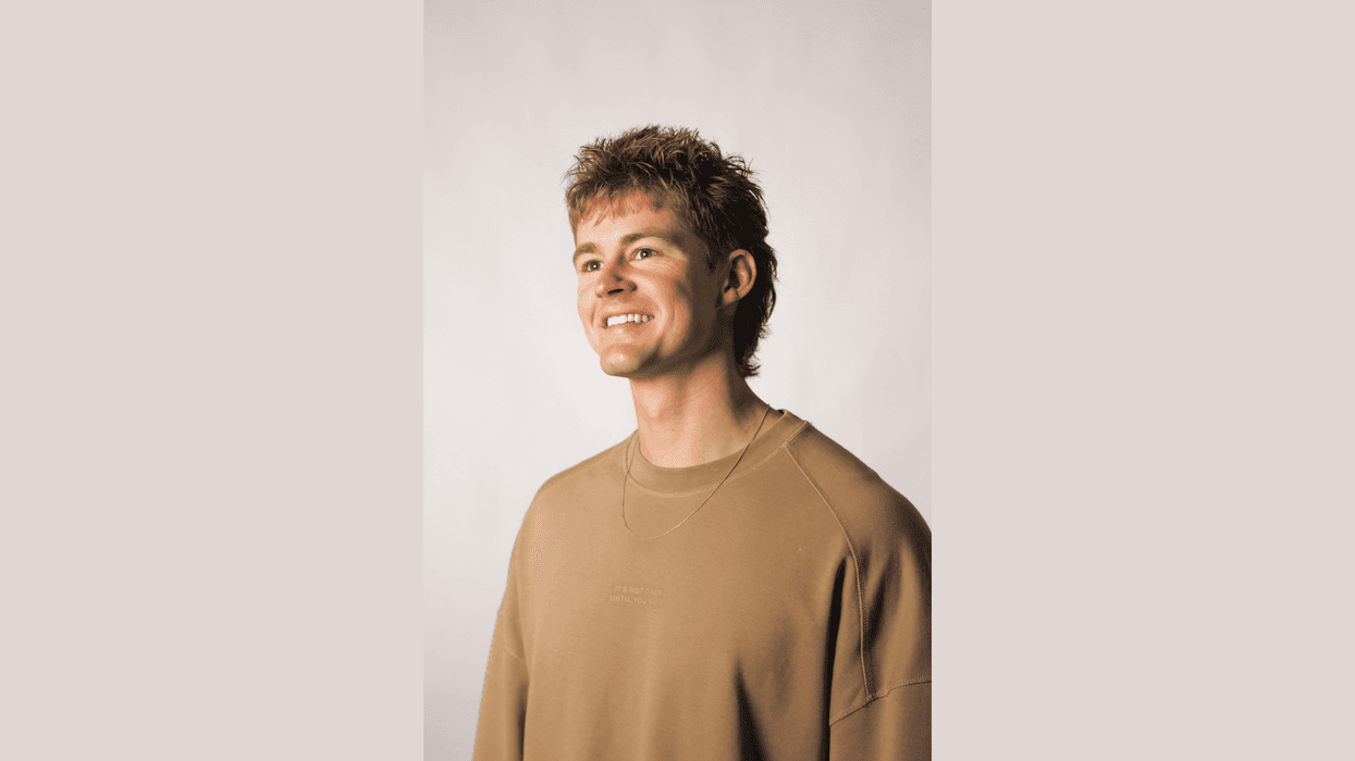 Smiling young man with textured hair in a brown sweatshirt, looking right.