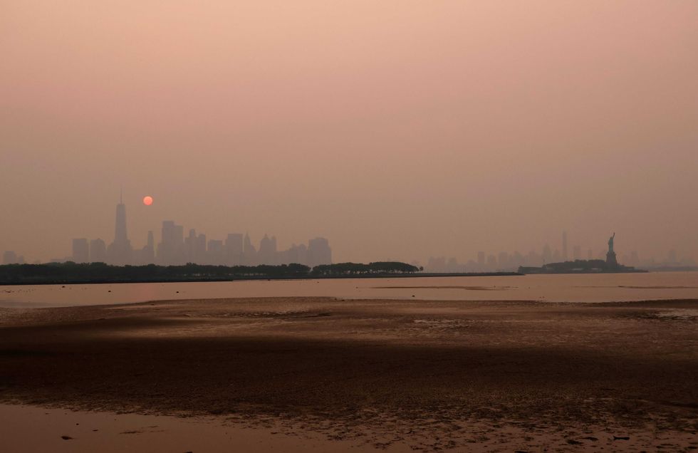 Smoke continues to shroud the sun as it rises behind the skyline of Lower Manhattan, Brooklyn and the Statue of Liberty in New York City on June 7, 2023