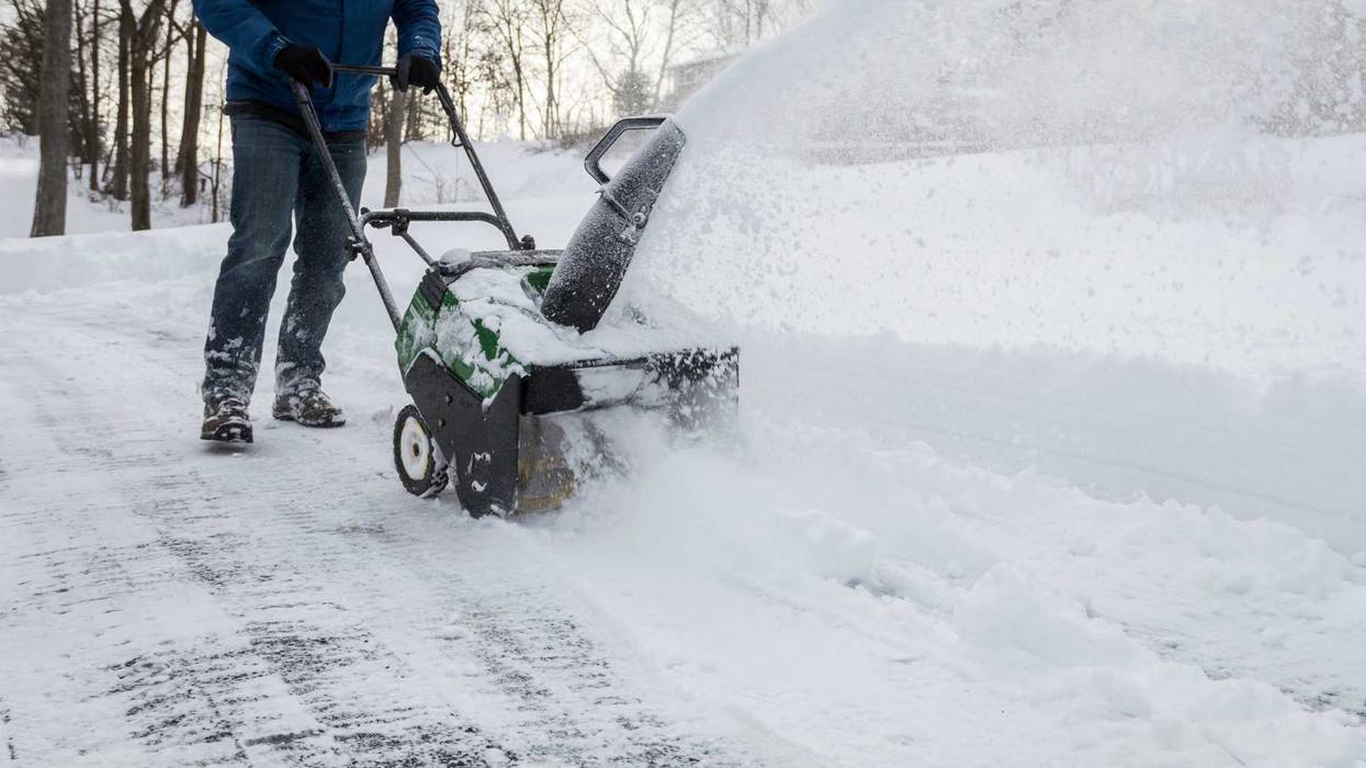 Snow blower in action clearing a residential driveway after snow storm
