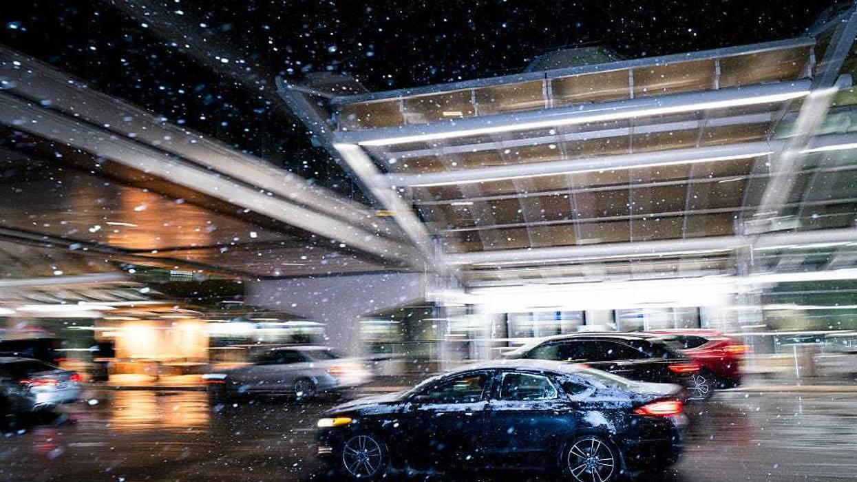 Snow falls as cars drop off travelers outside Minneapolis-Saint Paul International Airport in Minneapolis, Minnesota.